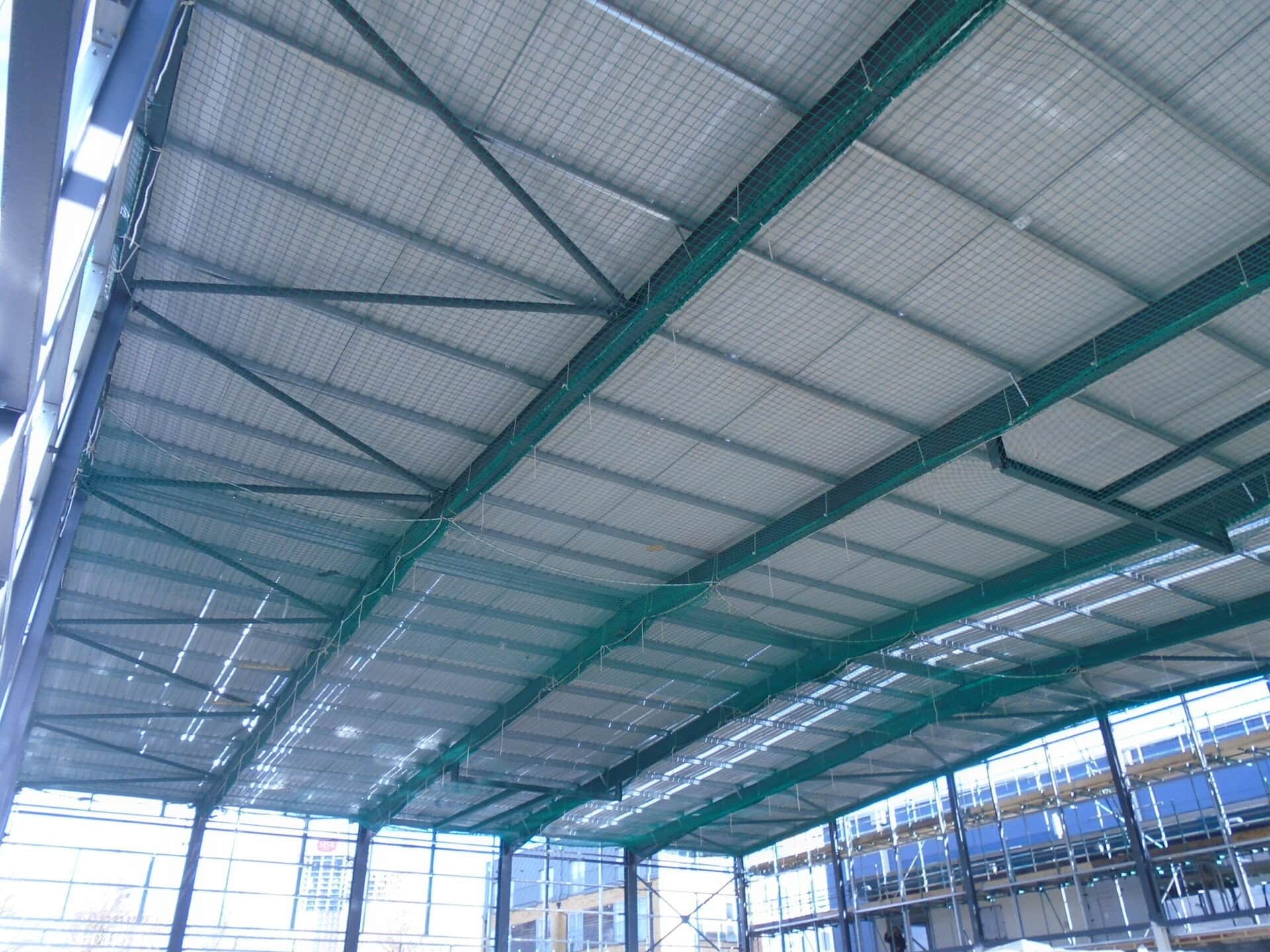 Safety netting rigged beneath roof steelwork, seen from below