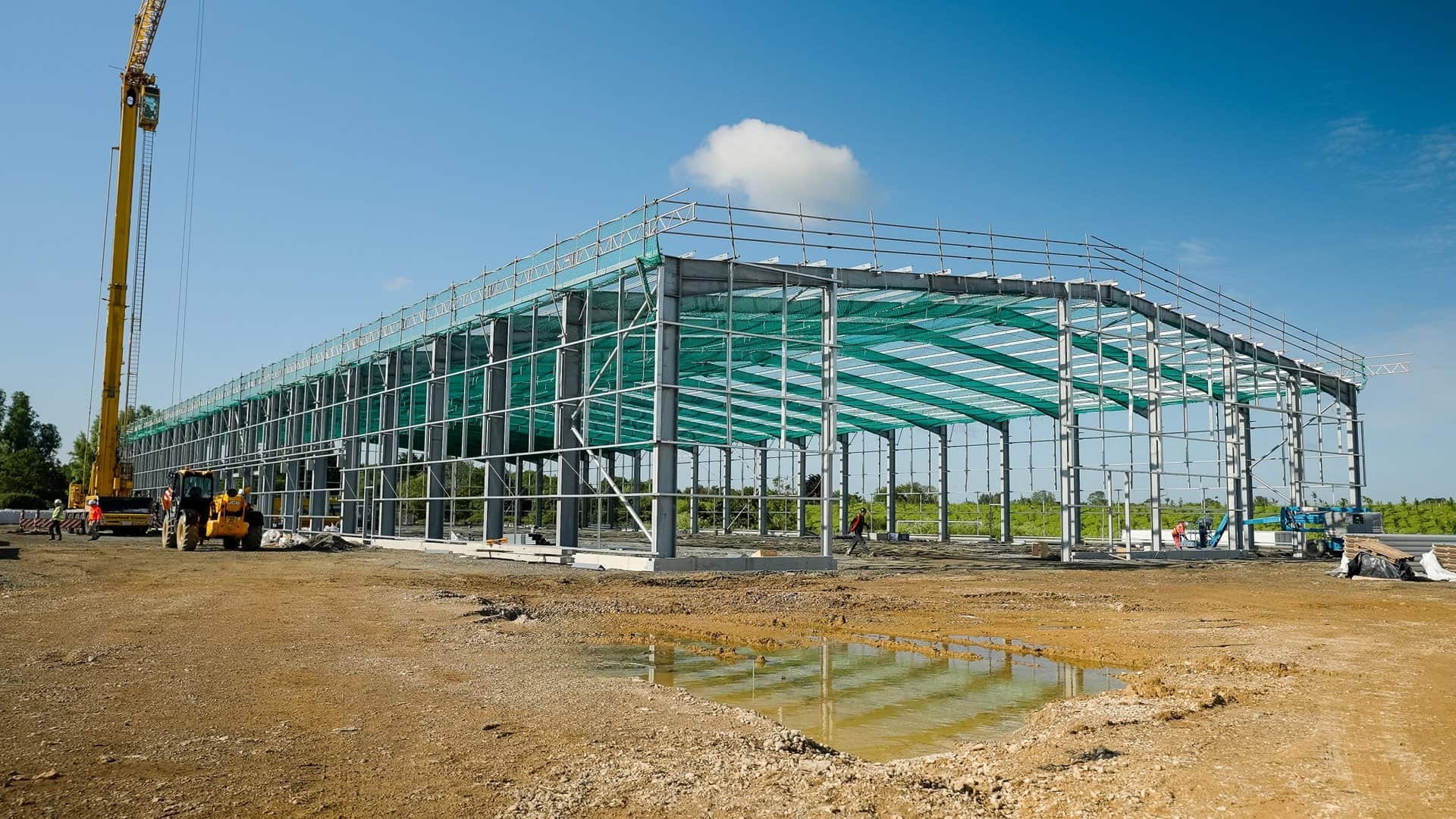 Steel-framed building with green safety netting installed below the roof